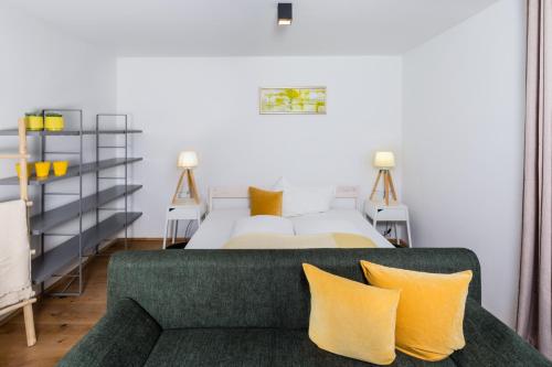 um quarto com uma cama e um sofá com almofadas amarelas em Apartment Macho em Innsbruck