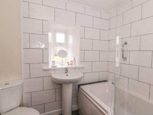 a white bathroom with a sink and a bath tub at Maesyfelin Isaf Apartment in Llanybydder