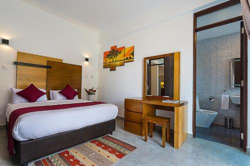 a bedroom with a bed and a desk and a bathroom at L'Aziz Suites in Nairobi
