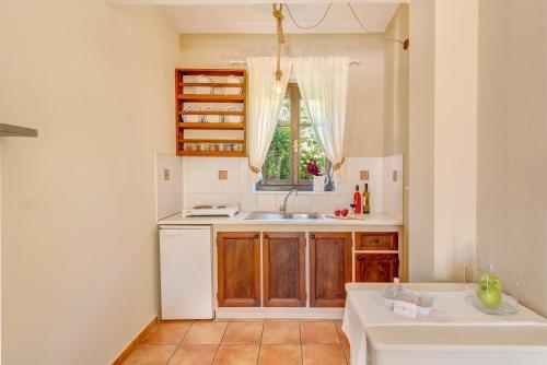 uma pequena cozinha com um lavatório e uma janela em Anemologio em Finikas