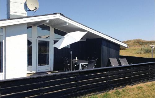 a house with a table and chairs and an umbrella at Holiday Home Hvide Sande 36 in Hvide Sande