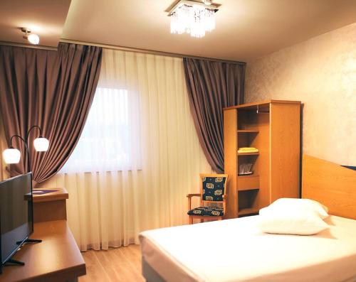 a hotel room with a bed and a desk and a television at Iris Hotel in Oradea