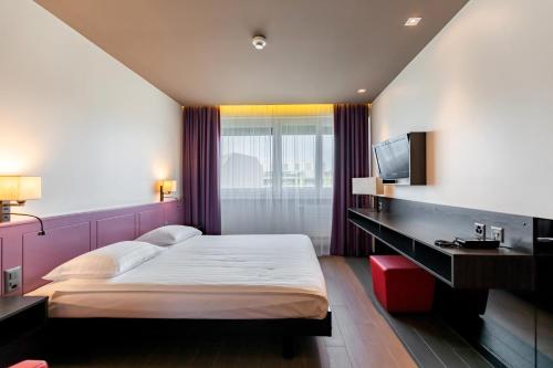 a bedroom with a large bed and a television at Hôtel Les Nations in Geneva