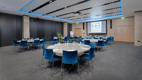 a conference room with tables and blue chairs and a screen at Hotel Budva in Budva