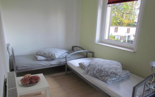 - 2 lits dans une chambre avec une fenêtre et une table dans l'établissement Ferienwohnung Apartement am Wolfsberg, à Reinhardtsdorf