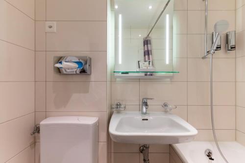 a bathroom with a sink and a toilet and a mirror at Hôtel Les Nations in Geneva