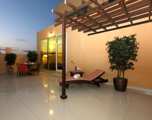 a patio with a bench and a table with a tree at Swiss Flora Inn Hotel Riyadh in Riyadh
