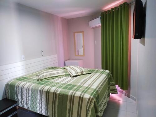 1 dormitorio con 1 cama y cortina verde en Caldas Novas - Prive das Thermas II - Apt 2 Qts suíte vista PQ AQUÁTICO, en Caldas Novas
