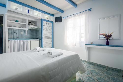 a white bedroom with a bed with towels on it at Orizontes Boutique Studios in Adamas