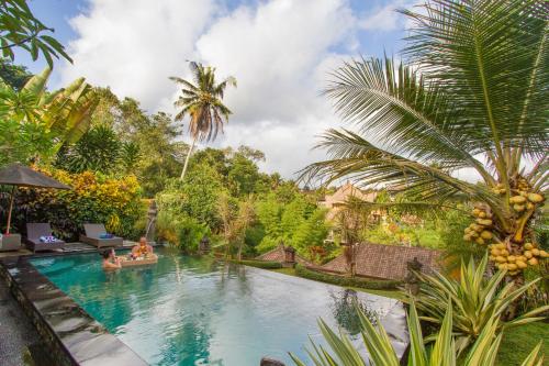 a pool at a resort with people in a boat in it at Kukuh House Ubud in Ubud