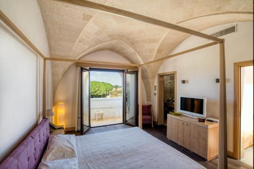 - une chambre avec un lit violet et une télévision dans l'établissement Masseria Bagnara Resort & Spa, à Marina di Lizzano