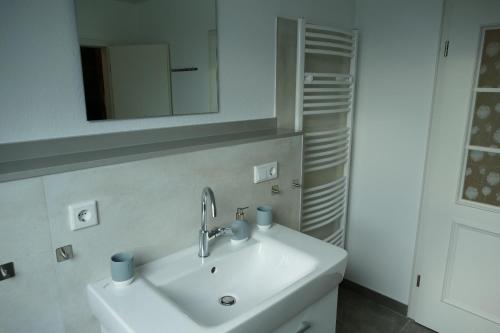 a white bathroom with a sink and a mirror at Ferienwohnung am Wulfkamp in Velen