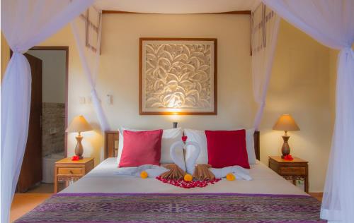 a bedroom with a large bed with red pillows at Kukuh House Ubud in Ubud