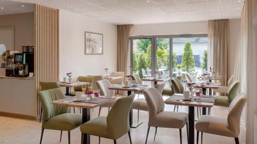 ein Restaurant mit Holztischen und -stühlen und einem Fenster in der Unterkunft Walhalla Hotel Regensburg Hoeferer 4 Sterne Superior in Regensburg