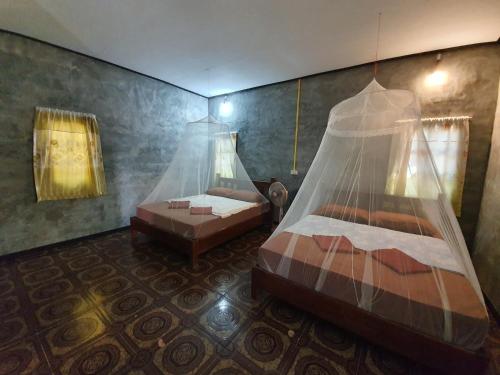 a bedroom with two beds with a mosquito net at Vijit Bungalow in Ko Phayam