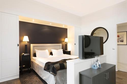 a bedroom with a bed and a flat screen tv at Elite Grand Hotel Norrköping in Norrköping
