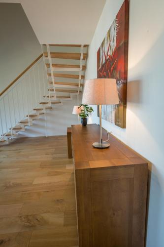 a lamp on a table in a hallway with a staircase at Apart Holidays - Marina Walensee in Unterterzen