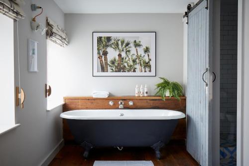 a bath tub in a bathroom with a picture on the wall at Artist Residence Cornwall in Penzance