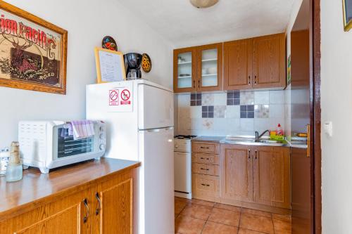 a kitchen with wooden cabinets and a white refrigerator at Mirta in Stara Baška