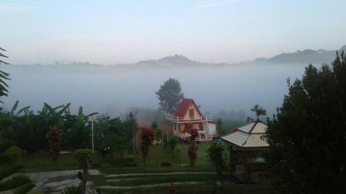 a house in the middle of a field in the fog at The Memory of Khaokho in Phetchabun