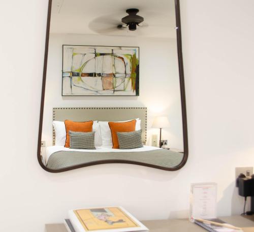 een spiegel aan de muur met een bed met kussens bij The Chronicle by Supercity Aparthotels in Londen