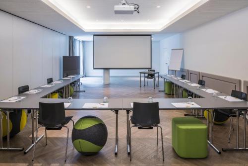 a conference room with tables and chairs and a projection screen at MAXX by Steigenberger Vienna in Vienna