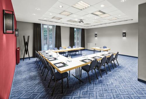 a conference room with long tables and chairs at MAXX Hotel Sanssouci Potsdam in Potsdam