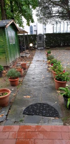 a garden path with a green house and potted plants at Civico 22 Pisa in Pisa
