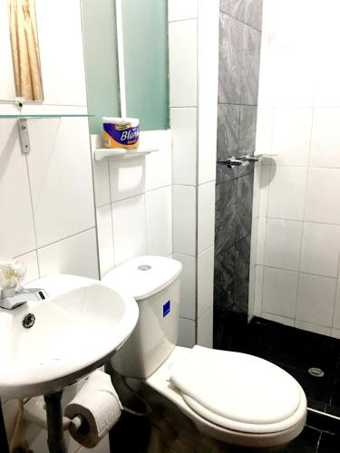 a bathroom with a white toilet and a sink at Hotel Casa Guillermo in Bogotá