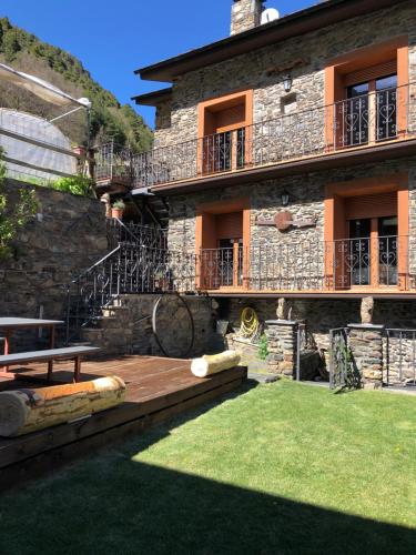 un grande edificio in pietra con un prato di fronte di Casa Rustica Cabanes a Ordino