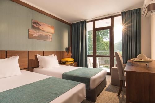 Cette chambre comprend deux lits et un bureau. dans l'établissement Hotel Pomorie Sun, à Sunny Beach
