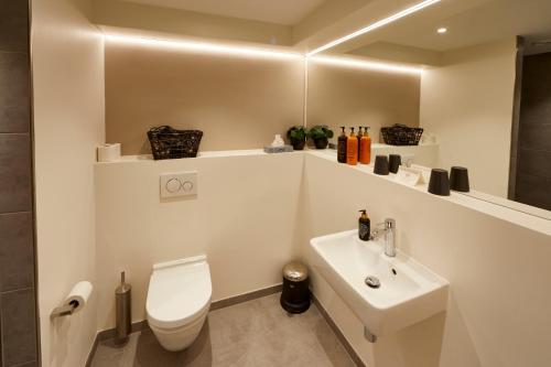 a white bathroom with a toilet and a sink at HimmerLand in Gatten