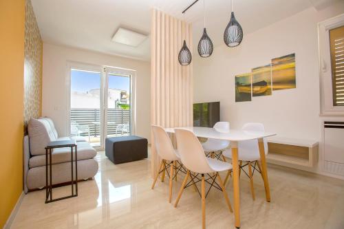 a white dining room with a table and chairs at Magic Stone Apartments in Baška Voda