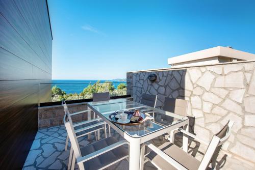 a glass table and chairs on the balcony of a house at Adria Lux Apartments Sveti Stefan in Budva