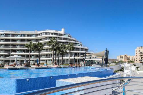 a large hotel with a swimming pool in front of a building at MyFlats Infinity View in Arenales del Sol