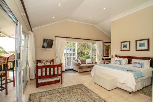 a bedroom with a bed and a couch and a window at Chartwell Guest House in Durban