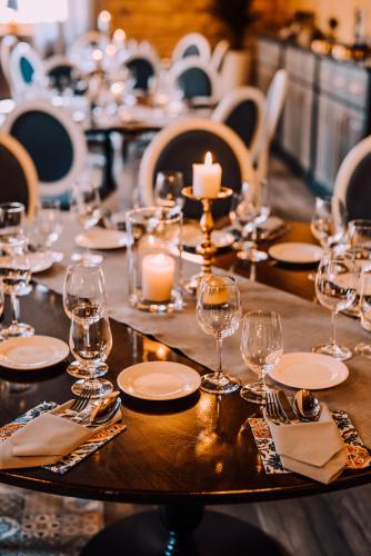 a table with glasses and plates and candles on it at Bahnhofs hotel in Alūksne