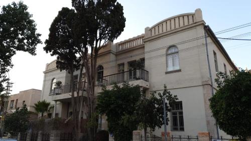 a white building with a tree in front of it at Ruby in Tel Aviv