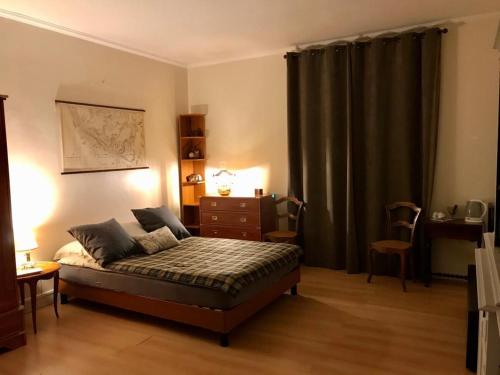a bedroom with a bed and a dresser and curtains at L ESCALE EN BEAUCE in Maisons