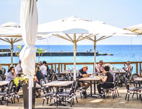 a group of people sitting at tables with the ocean in the background at Royal Suite Caesarea in Caesarea