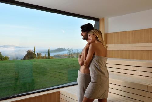 a man and a woman standing in front of a window at Borgobrufa Spa Resort Adults Only in Brufa