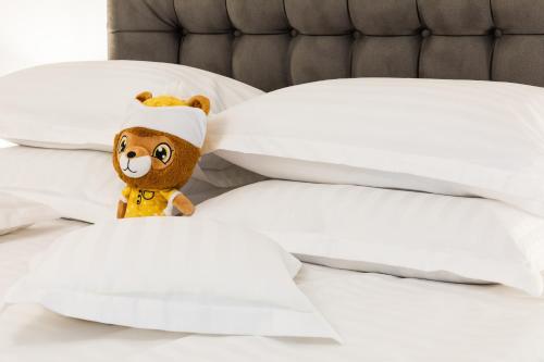a teddy bear sitting on a bed with pillows at Montana Residence in Poiana Brasov