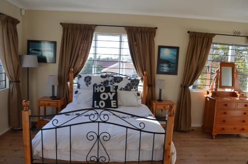 a bedroom with a bed and a dresser and a window at Whale Tale in Cape Town