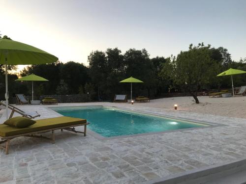 a swimming pool with chairs and umbrellas at Trulli Pietraverde in Ceglie Messapica