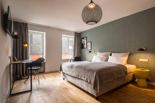 ein Schlafzimmer mit einem Bett und einem Schreibtisch mit einem Stuhl in der Unterkunft Genusshotel Krone & Roadtrips bei Basel in Inzlingen