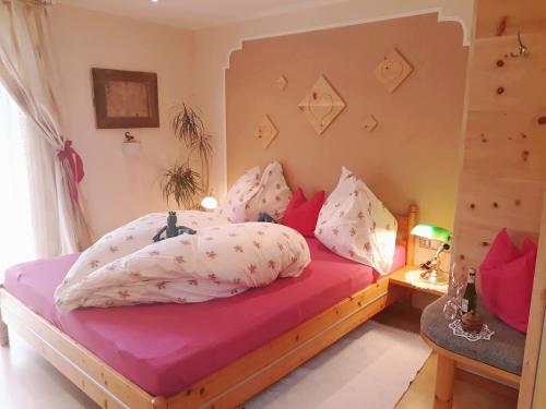 ニーダーンジルにあるFerienhaus Niedernsillのベッドルーム1室(ピンクと白の枕が備わるベッド1台付)