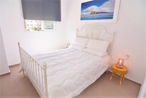 a white bed in a white room with a table at Cala de Benidorm Holidays in Cala de Finestrat