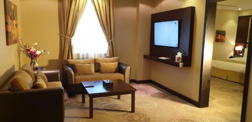 a living room with a couch and a tv in a hotel room at Swiss Flora Inn Hotel Riyadh in Riyadh