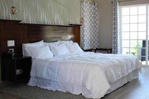a bedroom with a large white bed with a wooden headboard at Barefoot Caye Caulker Hotel in Caye Caulker