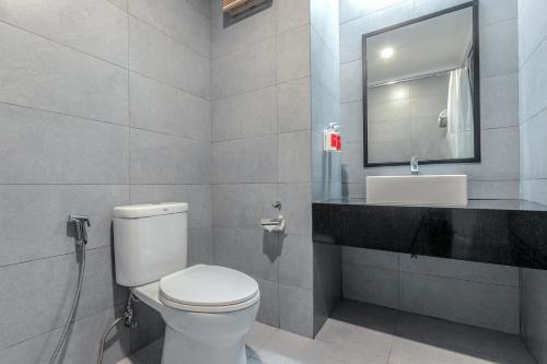 La salle de bains est pourvue de toilettes, d'un lavabo et d'un miroir. dans l'établissement OYO Townhouse 2 Hotel Gunung Sahari, à Jakarta